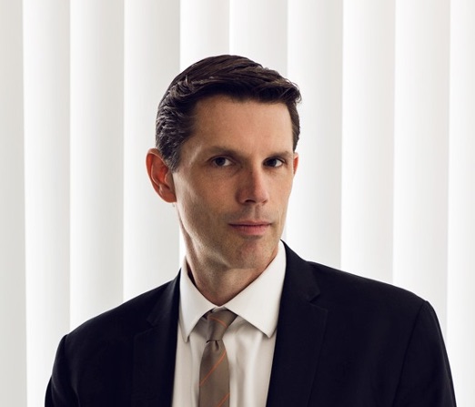 Image of a man in front of blinds