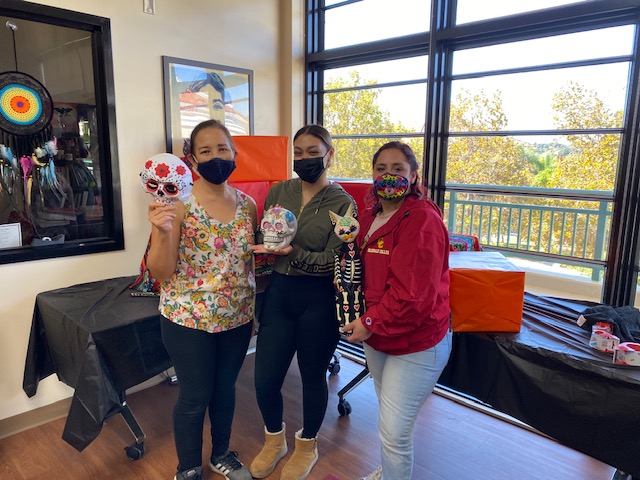 Three students holding up sugar skulls in the Multicultural center