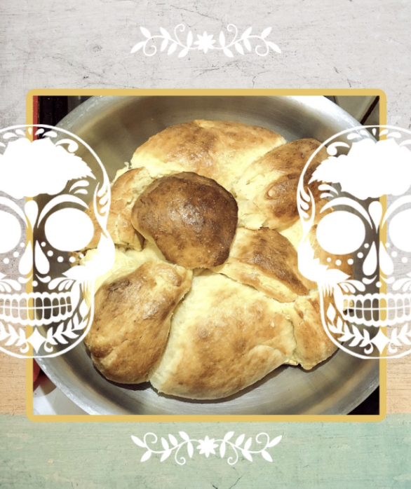 picture of pan de muerto with two white skulls on the left and right side.